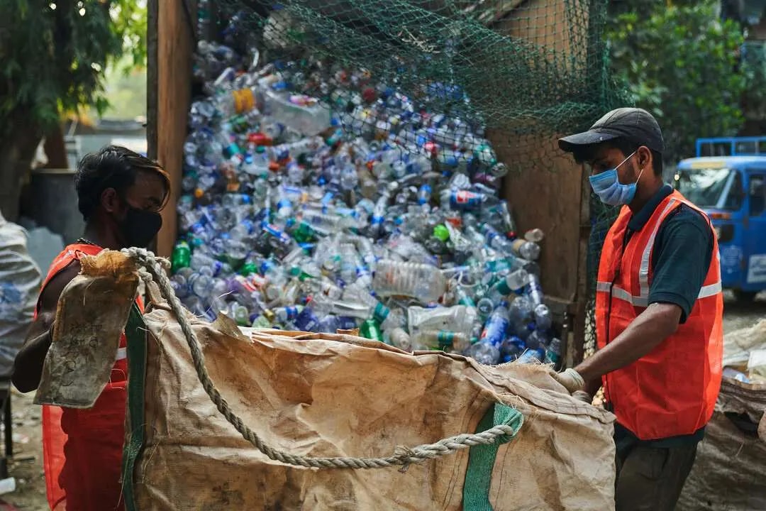Worker sorting a large pile of collected plastic bottles