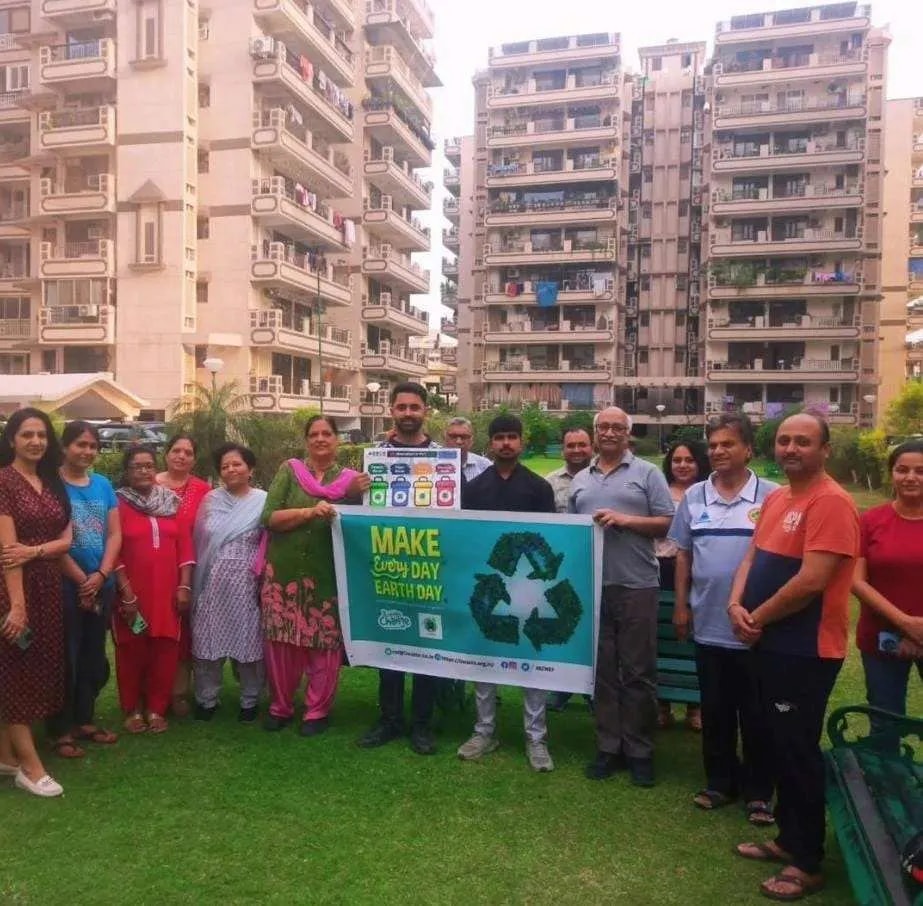 Residents of a housing society holding a 'Make every day Earth Day' banner